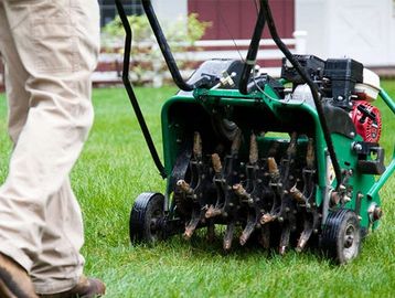 Worker aerating a lawn.