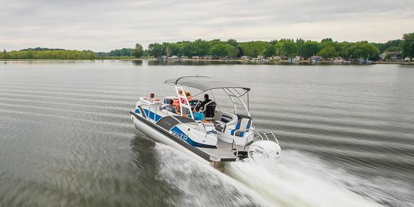A motorboat with passengers cruising on a calm lake under a cloudy sky.