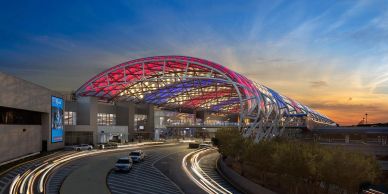 Modern airport terminal with vibrant lighting at sunset.