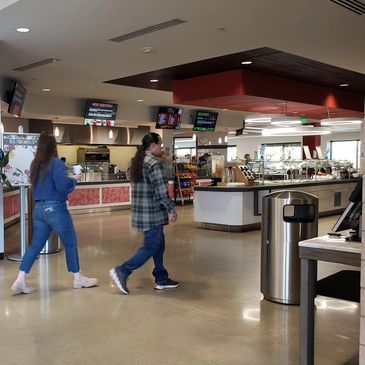 Two people walking into a corporate cafeteria.
