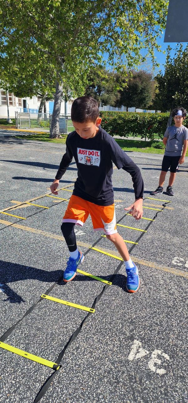 Boy in sportswear doing agility ladder drills outdoors.