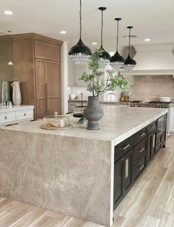 Modern kitchen island with pendant lights and vase.