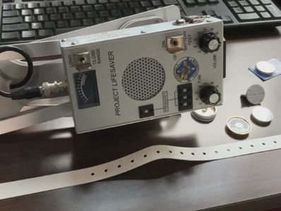 A Project Lifesaver device on a table with batteries and a keyboard.