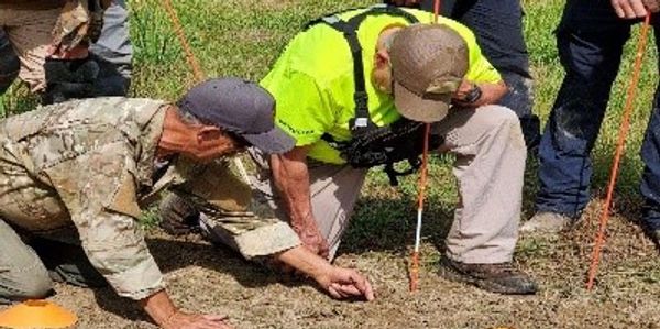 Team excavates soil with sticks and hands.