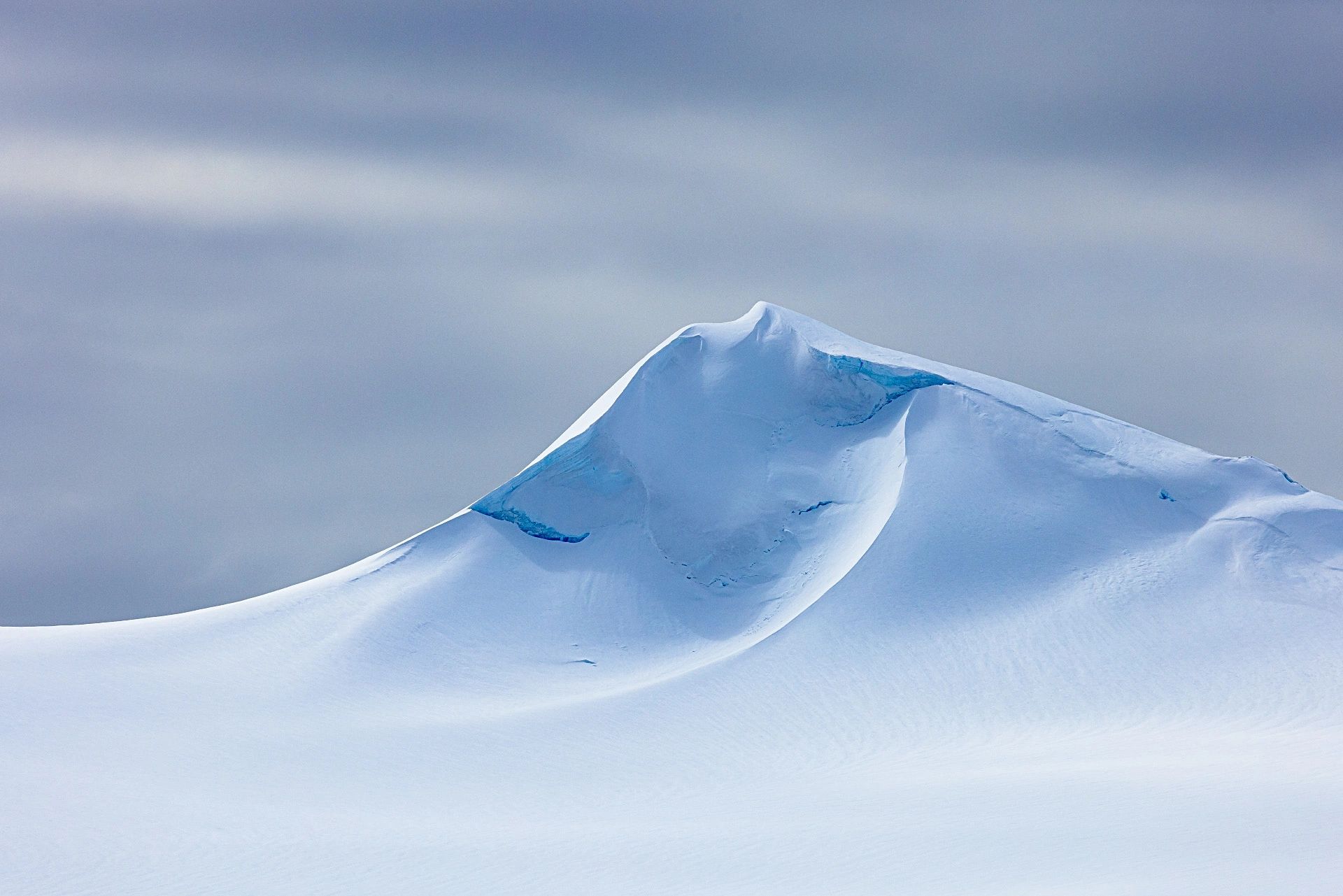 A snowy mountain peak beneath a cloudy sky.