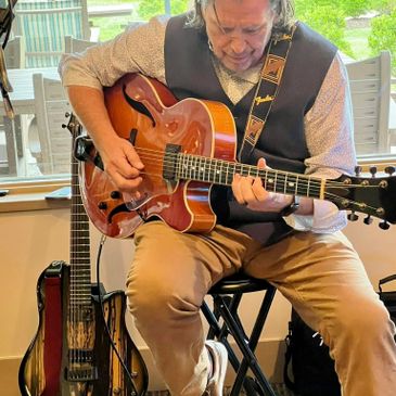 Man playing a semi-hollow electric guitar indoors.