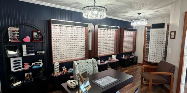 Modern eyeglasses store interior with wall displays and seating area.