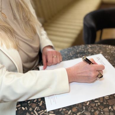 A woman signing a document at a table.