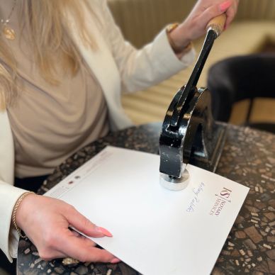 Person embossing a paper with a stamp press.