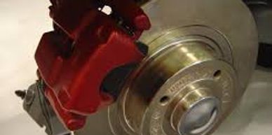 A red brake caliper with brake pad attached to brand new brake rotor.  It is not attached to a wheel, it is on display.  The floor is a shiny white