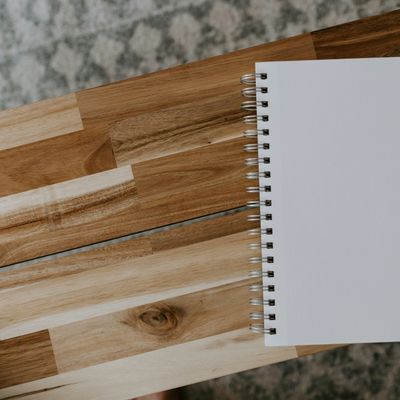 Blank spiral notebook on a wooden surface with a blurred patterned background.