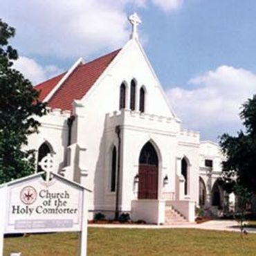 White church building with red roof and a sign.