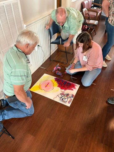 People working on a colorful art project on the floor.