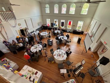 Community event with people seated around tables in a large room.