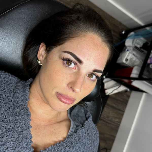 Woman lying on a chair wearing a gray textured top.