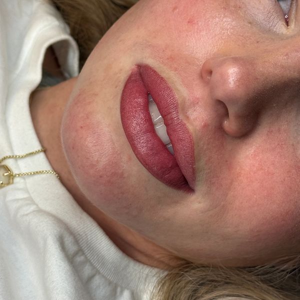 Close-up of lips with reddish lipstick.
