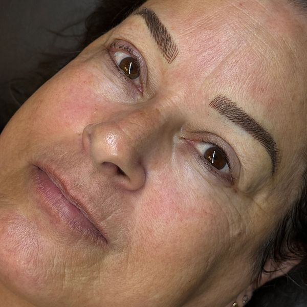 Close-up of a woman's face highlighting detailed skin texture and shaped eyebrows.