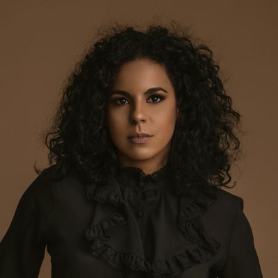 Portrait of a woman with curly hair and a serious expression.