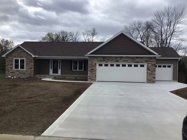 Modern single-story house with stone facade and large driveway.