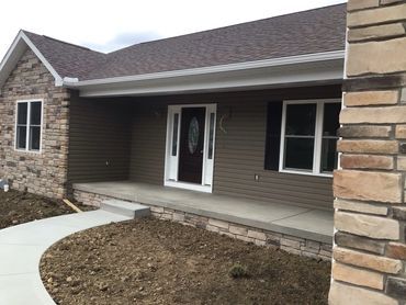 Newly constructed house exterior with stone accents and a clean porch.