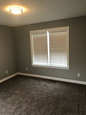 Empty room with gray walls, carpet, and window blinds.
