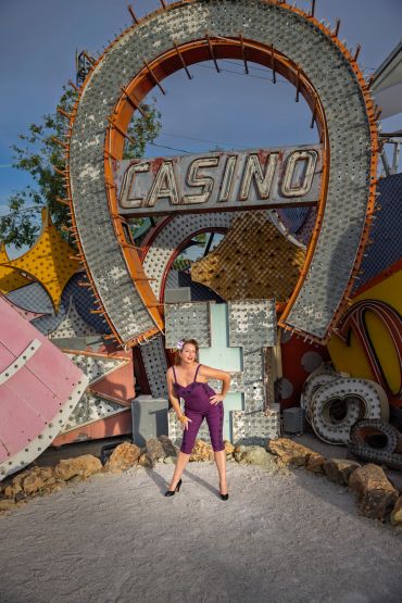 Woman posing in front of a vintage casino sign outdoors.