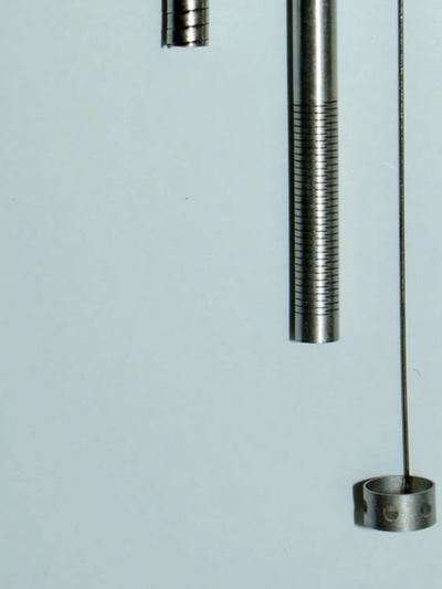 Close-up of metallic weights and a thin wire against a light background.
