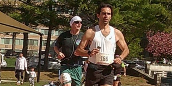 Two men running outdoors in a race, wearing numbered bibs.
