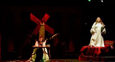 A theatrical scene with a red windmill and actors in dramatic costumes.