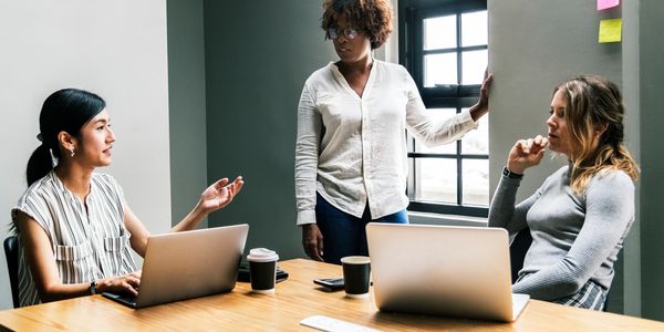 three women in a meeting room in discussion 