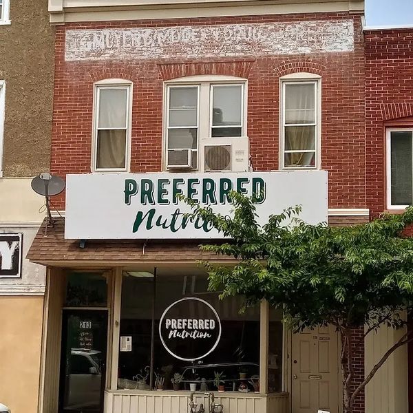 Brick building with "Preferred Nutrition" store and tree in front.