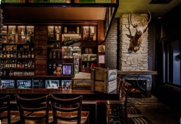 Cozy rustic bar interior with mounted deer head.