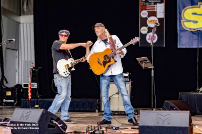 Two musicians fist bump on stage during a performance.