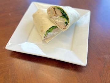 Chicken wrap sandwich cut in half on a white plate.