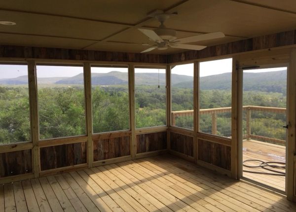 Screened porch with wooden flooring and scenic mountain views.
