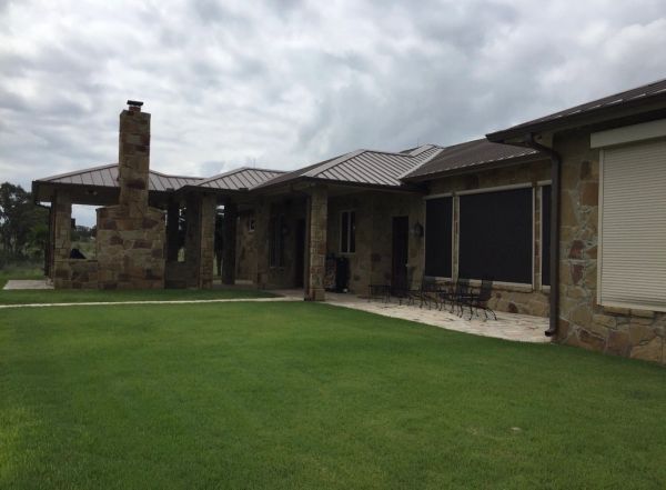 Stone house with a green lawn under cloudy skies.