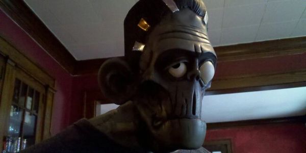 A close-up of a Frankenstein monster mask in a dimly lit room.