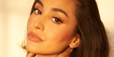 Close-up of a woman with glowing makeup and soft lighting.