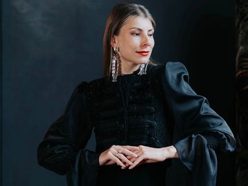 Femme élégante en robe noire avec de grandes boucles d'oreilles.