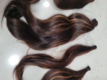 Bundles of dark brown hair extensions with lighter highlights.