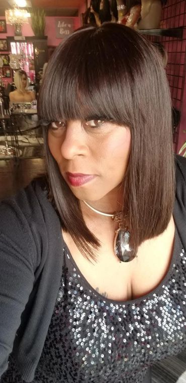 Woman with straight hair and bangs wearing a sequin top and necklace.