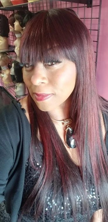 Woman with straight burgundy hair and bangs.