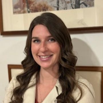 Smiling woman with long curly hair indoors.
