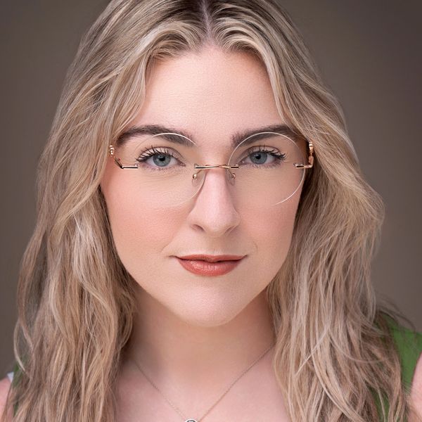 Close-up portrait of a confident woman with glasses and blonde hair.