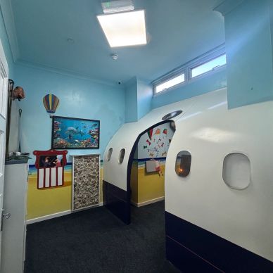 Indoor playroom with airplane-themed structure.