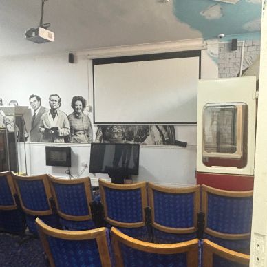 Small classroom with blue chairs and multimedia equipment.