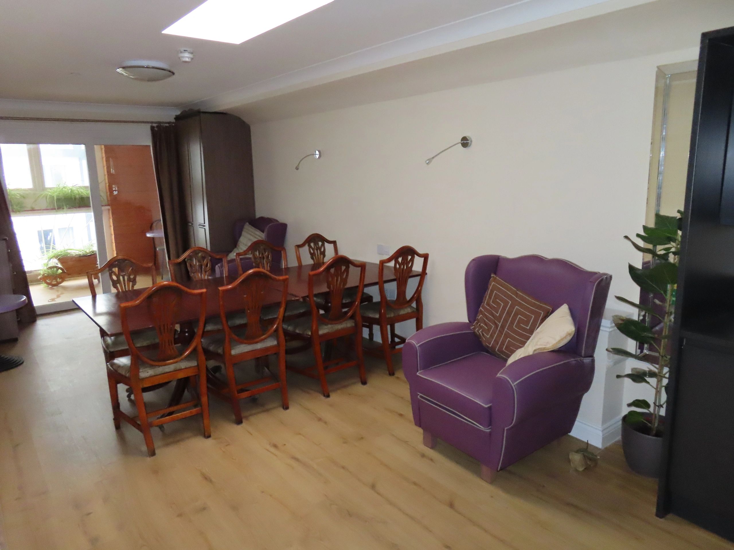 Dining room with wooden chairs and purple armchairs.