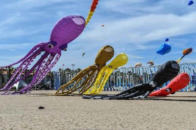 Colorful octopus-shaped kites flying over a sandy beach on a windy day.