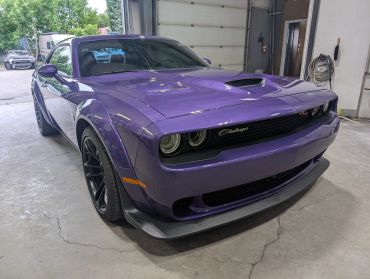 Purple Dodge Challenger parked inside a garage.
