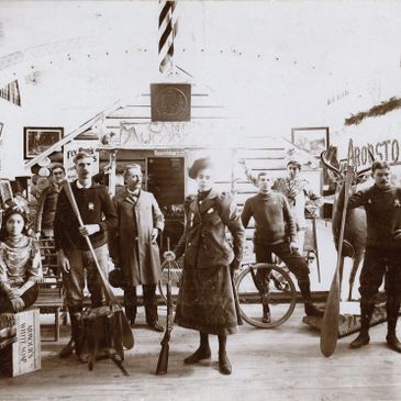 Vintage group photo of people with various objects and weapons in an indoor setting.